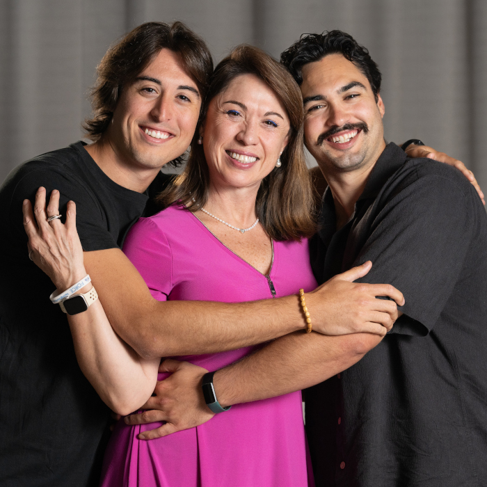 A woman being hugged by her two adult sons